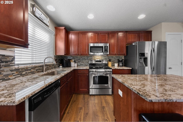 15574 Bachelor Ave, Sandy, OR 97055 - kitchen with appliances with stainless steel finishes, dark wood-style floors, light stone countertops, decorative backsplash, and a textured ceiling