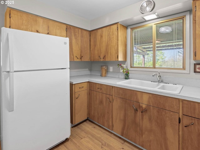 6229 NW Skyline Blvd, Portland, OR 97229 - kitchen featuring a sink, brown cabinetry, light countertops, light wood-style flooring, and freestanding refrigerator