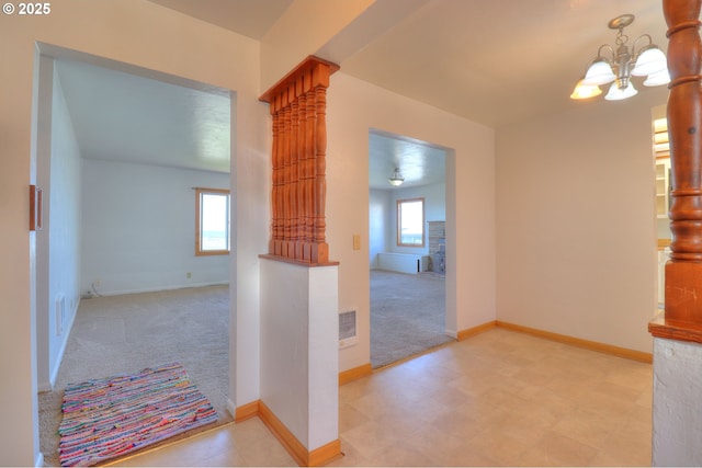 foyer entrance featuring a chandelier, carpet, and baseboards