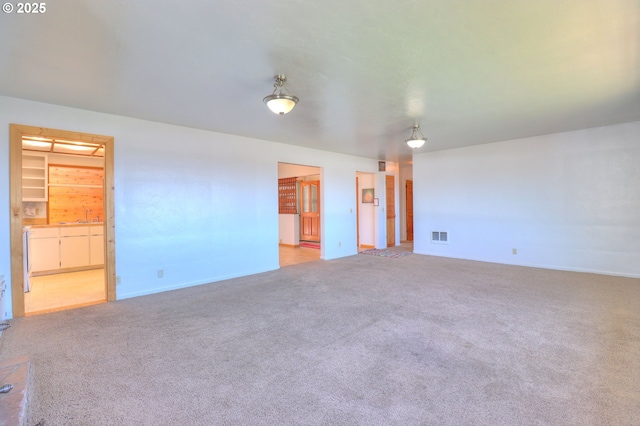 carpeted spare room with baseboards and a sink