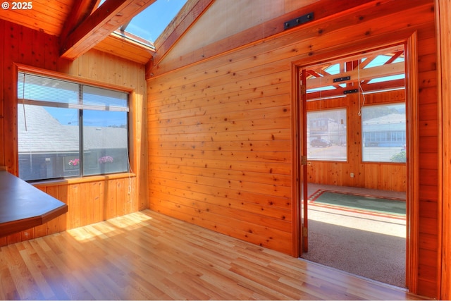 spare room featuring healthy amount of natural light, a skylight, and wood walls