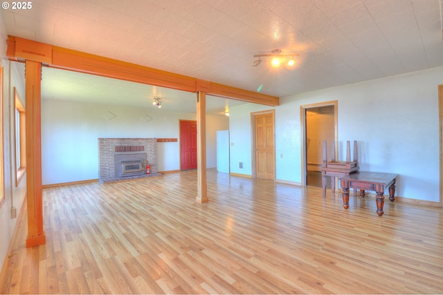 unfurnished living room featuring light wood-style flooring, baseboards, and a fireplace
