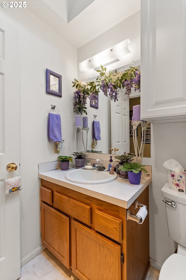 half bath with toilet, vanity, and baseboards