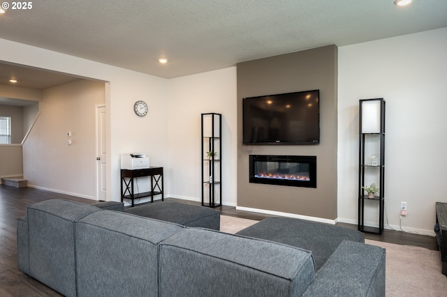 living room featuring a glass covered fireplace, baseboards, wood finished floors, and recessed lighting