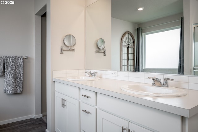 bathroom featuring double vanity, wood finished floors, baseboards, and a sink