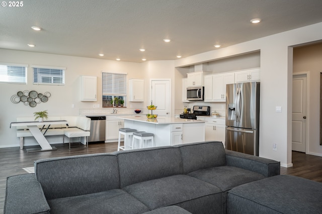 living area with a healthy amount of sunlight, recessed lighting, dark wood-style flooring, and baseboards