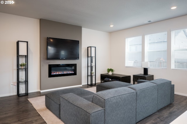 living room with visible vents, dark wood-type flooring, a glass covered fireplace, recessed lighting, and baseboards