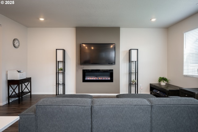 living room with a glass covered fireplace, dark wood-type flooring, recessed lighting, and baseboards