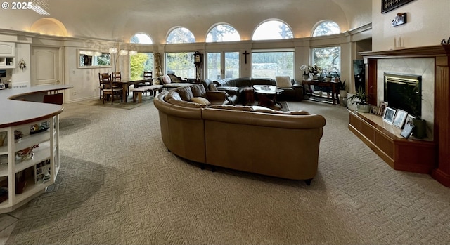 living room featuring carpet, a fireplace, and a towering ceiling