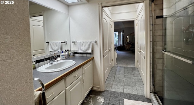 full bathroom featuring a skylight, a textured wall, a shower stall, and vanity