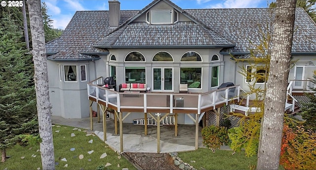 back of house featuring a patio area, a tiled roof, a chimney, and stucco siding