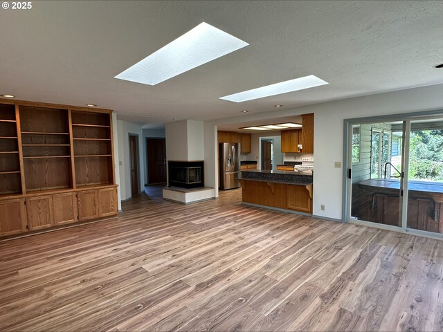 3115 Deer Trail Ln, Medford, OR 97501 - unfurnished living room featuring a textured ceiling, wood finished floors, a skylight, and a healthy amount of sunlight