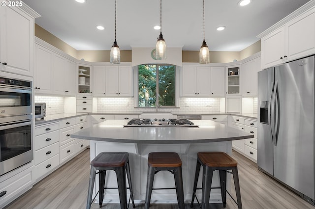 11712 Finnegans Way, Oregon City, OR 97045 - kitchen featuring appliances with stainless steel finishes, white cabinets, a kitchen bar, tasteful backsplash, and recessed lighting