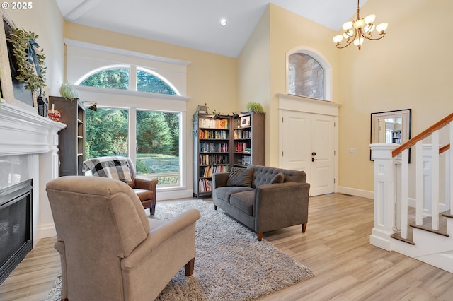 11712 Finnegans Way, Oregon City, OR 97045 - living area featuring high vaulted ceiling, a glass covered fireplace, stairway, light wood-type flooring, and a chandelier