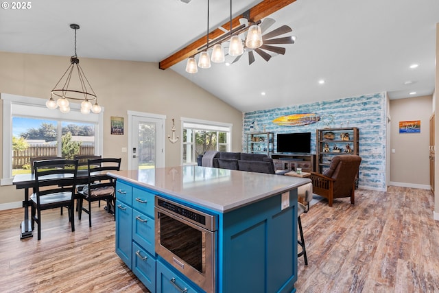 875 12th St SW, Bandon, OR 97411 - kitchen featuring blue cabinetry, stainless steel microwave, a chandelier, light wood-type flooring, and a kitchen island