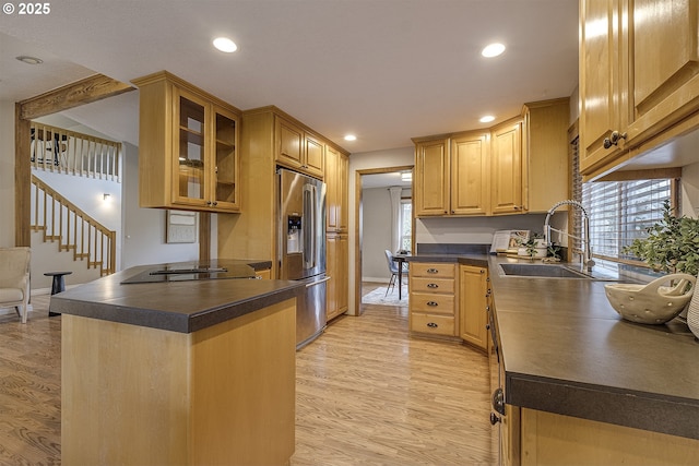 kitchen with a sink, dark countertops, stainless steel refrigerator with ice dispenser, and light wood finished floors