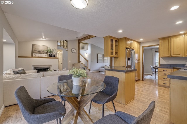 dining area featuring recessed lighting, light wood-style flooring, a fireplace, and lofted ceiling