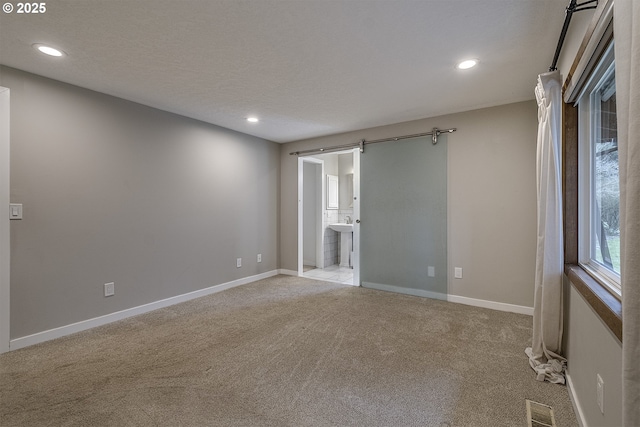 empty room with baseboards, recessed lighting, a textured ceiling, visible vents, and light colored carpet