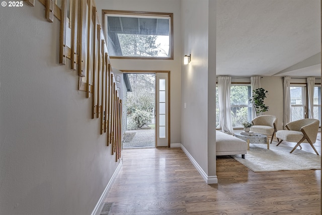 entrance foyer with visible vents, baseboards, a textured ceiling, and wood finished floors