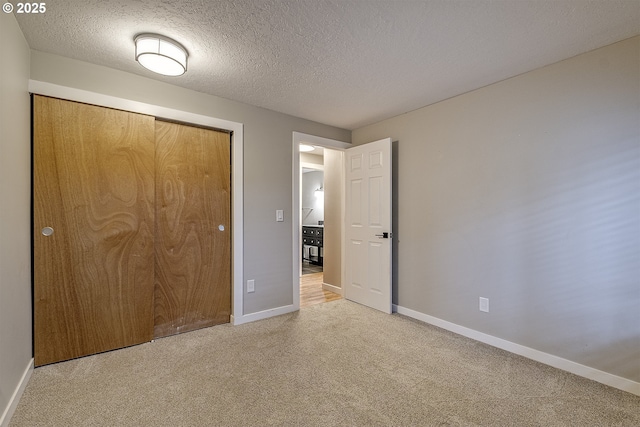 unfurnished bedroom featuring light carpet, baseboards, and a textured ceiling