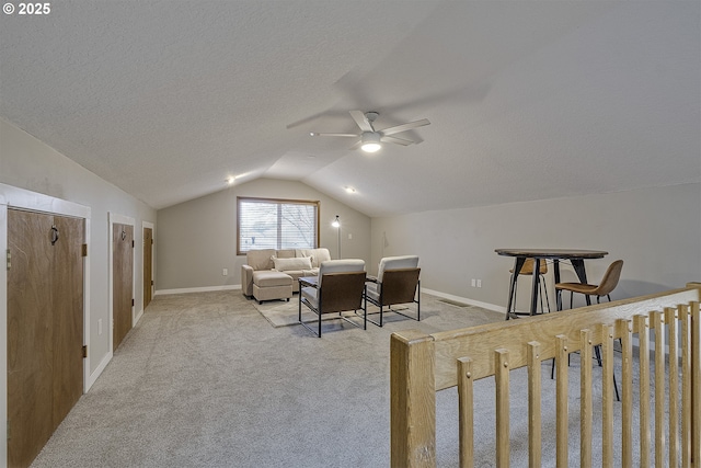 sitting room with baseboards, a ceiling fan, a textured ceiling, vaulted ceiling, and light colored carpet