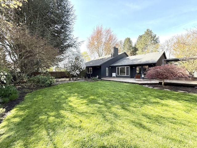 rear view of property featuring a chimney, a patio area, fence, and a lawn