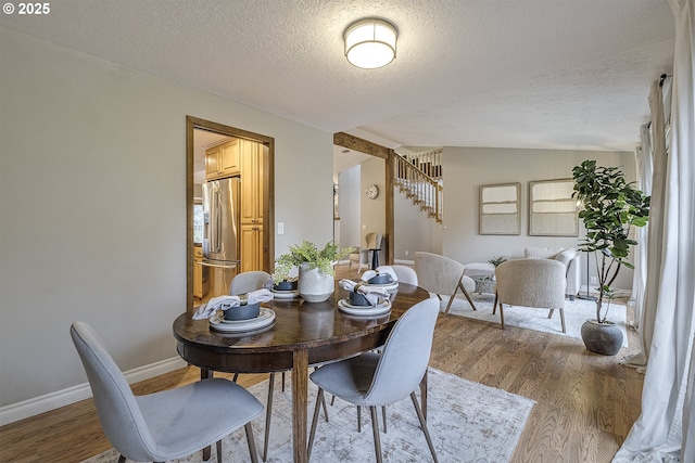 dining space with baseboards, stairs, lofted ceiling, and wood finished floors