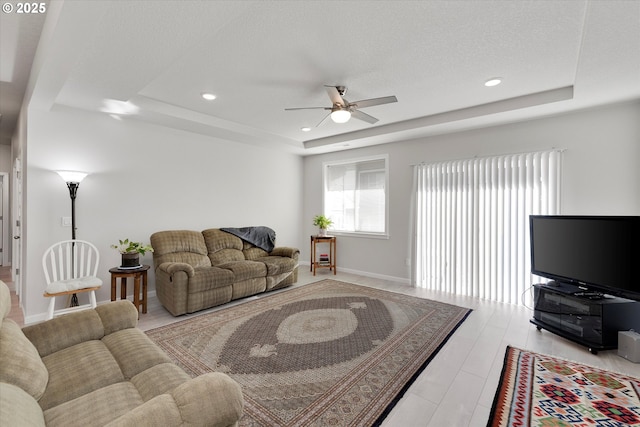 living room featuring a tray ceiling, light hardwood / wood-style flooring, and ceiling fan