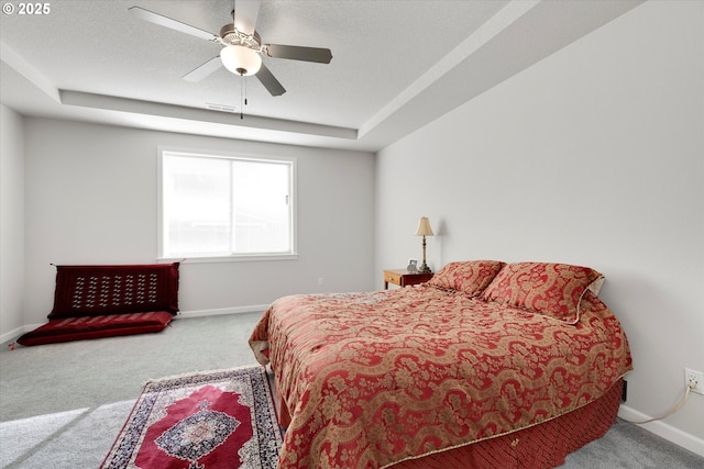 bedroom with a raised ceiling, ceiling fan, and carpet flooring