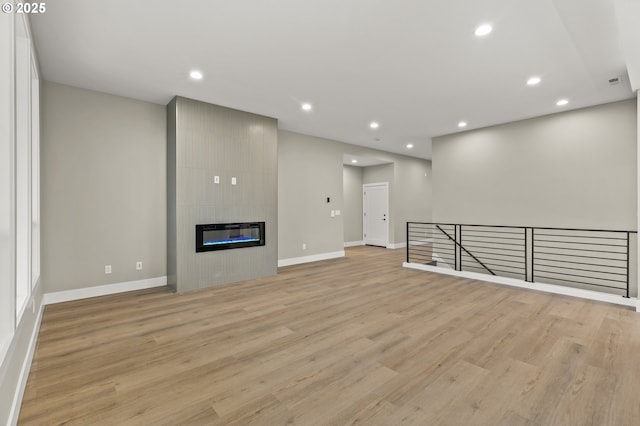 unfurnished living room with a large fireplace and light wood-type flooring