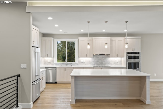 kitchen with white cabinetry, appliances with stainless steel finishes, sink, and hanging light fixtures