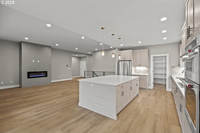 kitchen with pendant lighting, a fireplace, white cabinetry, a center island, and high end fridge