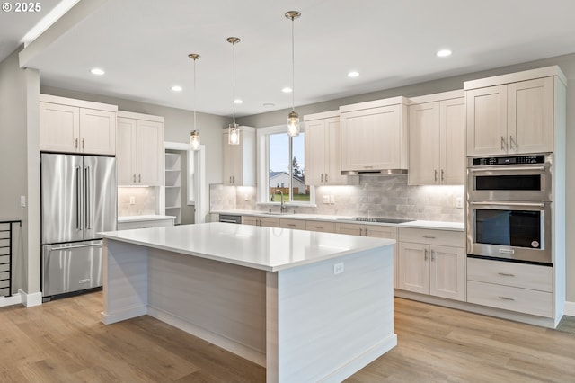 kitchen with sink, a center island, hanging light fixtures, appliances with stainless steel finishes, and white cabinets