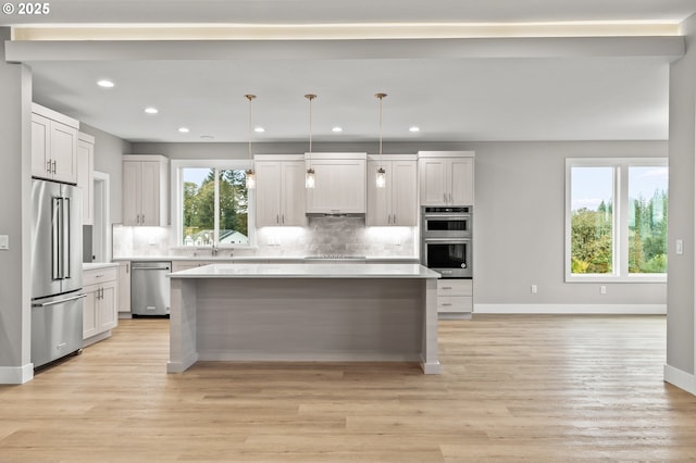 kitchen featuring a kitchen island, decorative light fixtures, white cabinets, backsplash, and stainless steel appliances