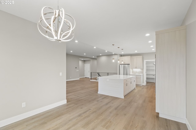 kitchen featuring a kitchen island, pendant lighting, stainless steel fridge, and light hardwood / wood-style floors