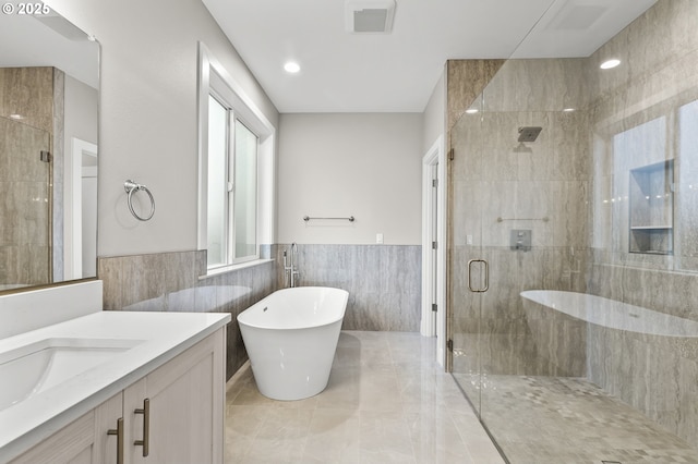 bathroom featuring shower with separate bathtub, tile walls, and vanity