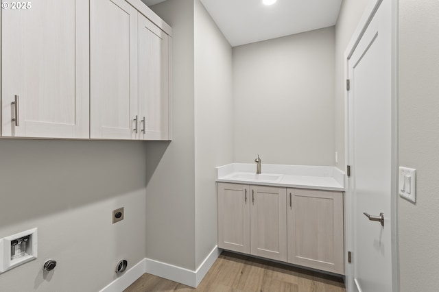 laundry area featuring cabinets, sink, light hardwood / wood-style flooring, and electric dryer hookup