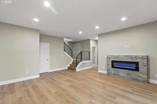 unfurnished living room with a stone fireplace and light wood-type flooring