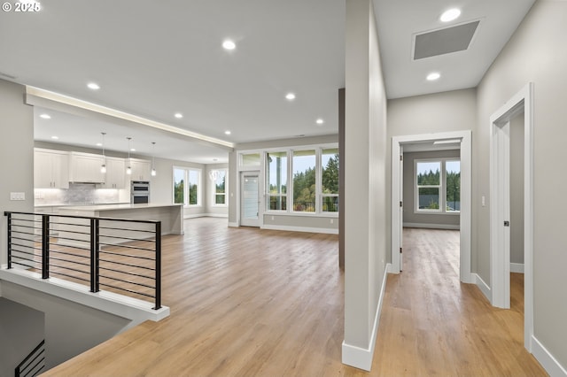 hall featuring a wealth of natural light and light hardwood / wood-style floors