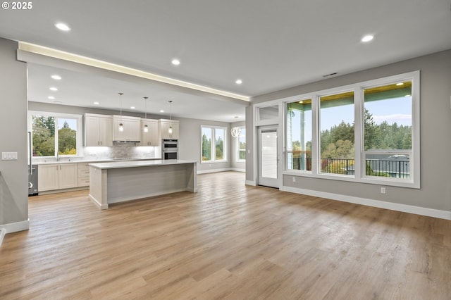 kitchen featuring hanging light fixtures, light hardwood / wood-style floors, a center island, and white cabinets