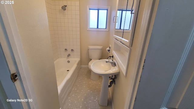 bathroom featuring tile patterned flooring, toilet, and shower / washtub combination