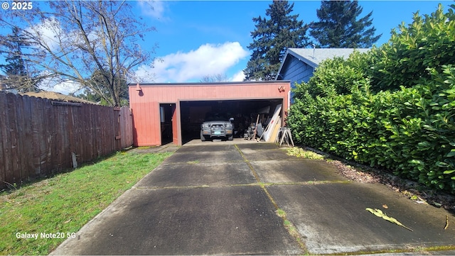 garage featuring concrete driveway and fence