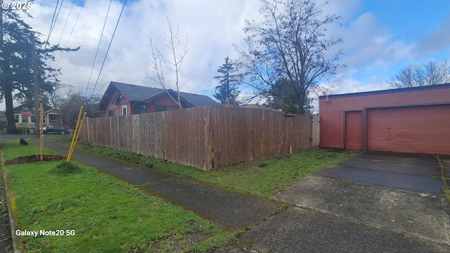 exterior space featuring an outdoor structure, fence, and driveway