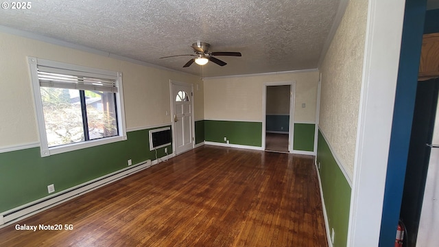 spare room featuring a baseboard heating unit, wood finished floors, a textured wall, a textured ceiling, and a ceiling fan