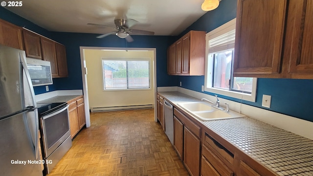 kitchen with a wealth of natural light, a baseboard radiator, appliances with stainless steel finishes, and a sink