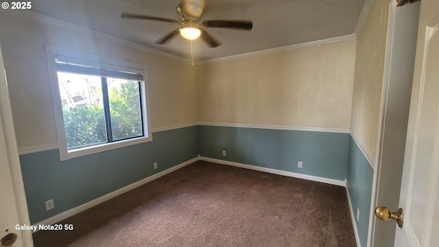 empty room with dark colored carpet, baseboards, ornamental molding, and a ceiling fan