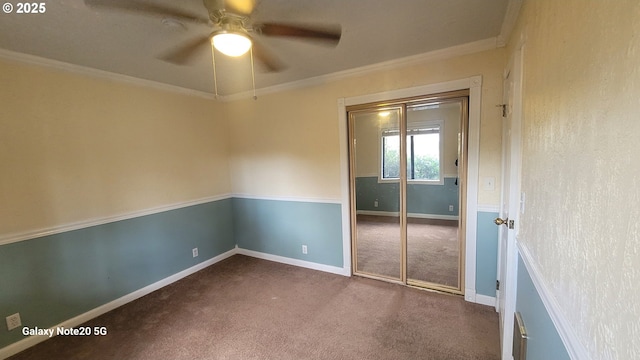 unfurnished room featuring crown molding, baseboards, dark colored carpet, and ceiling fan