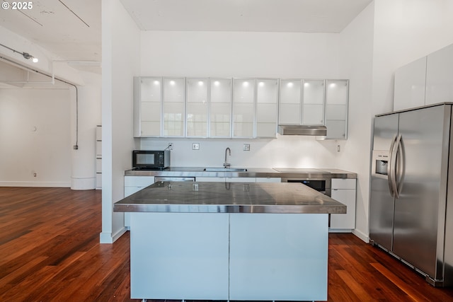 kitchen with stainless steel countertops, stainless steel fridge with ice dispenser, under cabinet range hood, white cabinetry, and modern cabinets