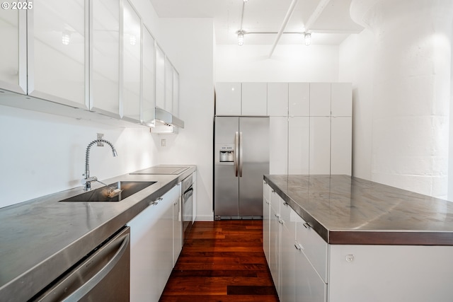 kitchen featuring modern cabinets, a sink, stainless steel countertops, white cabinetry, and appliances with stainless steel finishes