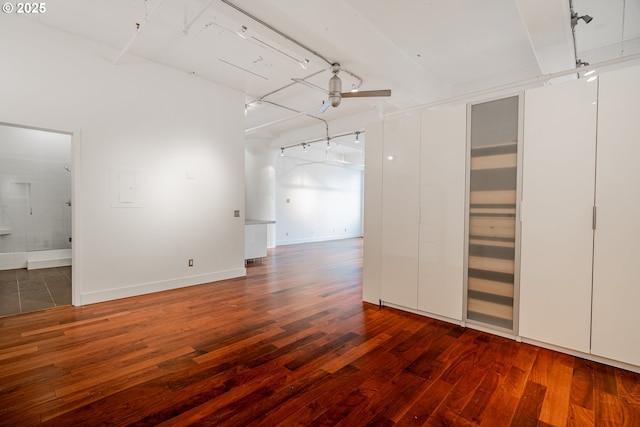 spare room featuring beamed ceiling, rail lighting, baseboards, and hardwood / wood-style floors